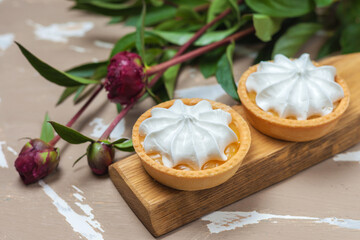 Fototapeta na wymiar Lemon tart. Two cakes on a wooden plate and three peony flowers