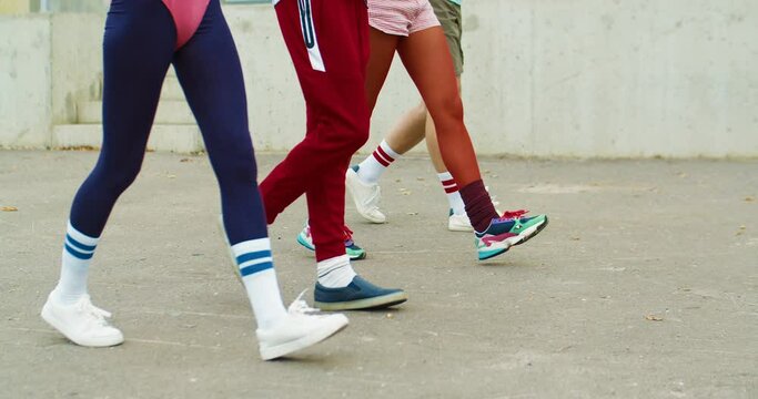 Happy funny Caucasian vintage male and female athletes doing walking exercise on street. Joyful men and girl in retro style clothes walking outdoors. Group workout. Sporty lifestyle. 70s concept