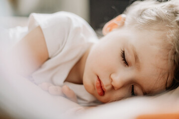 Fototapeta na wymiar Portrait of a little blond girl sleeping in her crib. Concept of healthy regular daytime sleep for children