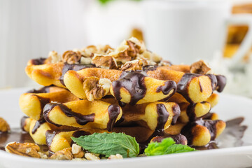 Breakfast in cafe - Belgian waffles with sauce and a cup of tea on a wooden table in room