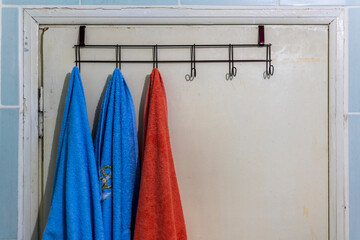Hanging towels on a worn wooden bathroom door. Copy space for text.
