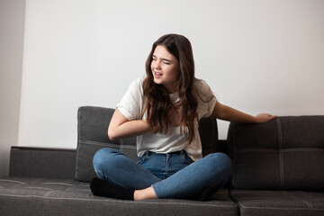 Obraz premium young beautiful brunette woman sitting on the sofa suffering from extreme pain in chest looking desperate, healthcare and medical concept