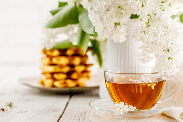 Breakfast in cafe - Belgian waffles with sauce and a cup of tea on a wooden table in room