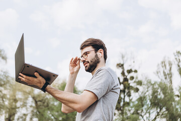 handsome bearded man in glasses freelancer working on a laptop outdoors in the mountains. Freelance concept