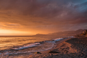 Beach at sunset with beautiful reflections, clouds and mountains on horizon. Touristic destination.