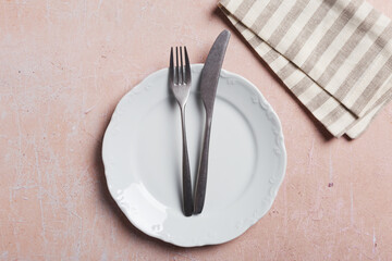Table set with silverware on pink concrete with napkin