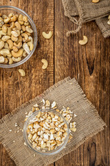 Wooden table with chopped Cashew nuts (close-up shots, selective focus)