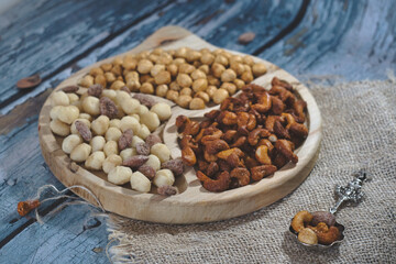 Variety of delicious nuts as heathy vegan appetizer - brazil nuts with chili, walnuts with garlic, sweet caramelized almond with cinnamon and macadamia on a rustic wooden board