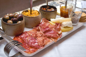  selection of best appetizers of Portugal food or portuguese tapas - smoked ham, salami, chorizo sausages, a variety of cheese, crackers, liver pate and several traditional kinds of jam