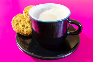 Cup of coffee and cereal cookies on a pink background