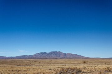 Fototapeta na wymiar View of distant mountains across high desert plain in New Mexico USA, horizontal aspect