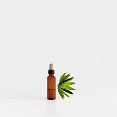 Natural cosmetic bottle on gray background with green plant. New normal concept. Balancing composition from figures. Natural, beauty body health cosmetic products.