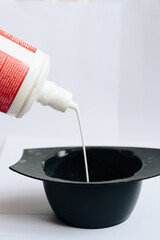 stylist kneads hair dye in a black container close up