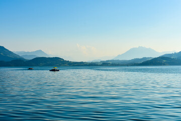 ZUG, SWITZERLAND - August 26, 2019: View of Lake Zug from Zug with touristic boat on the watter and mountains - Alps in the background.
