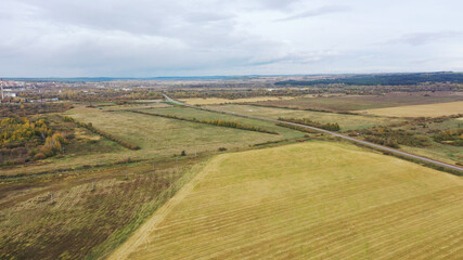 Naklejka premium Aerial drone view agriculture crops wheat filed with road and cars. Highway road through field and meadow Landscape. Top View of cars In motion on road. Travel Trip Concept.