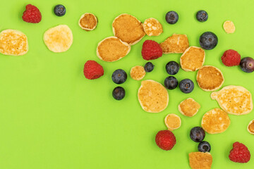 A bowl with mini pancake cereal. Trendy food. Tiny cereal pancakes with blueberries and raspberries. Copy space