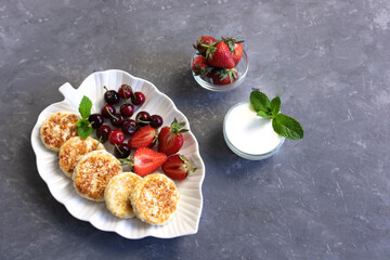 delicious curd pancakes or cheese pancakes with berries of cherry and strawberry, sprinkled with powdered sugar, healthy breakfast concept, top view
