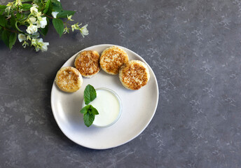 Cheesecakes, curd pancakes or cheese pancakes with mint and sour cream, low-calorie breakfast, flat lay, horizontal orientation