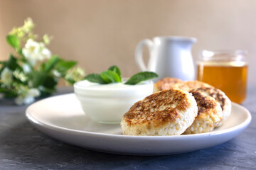 cheese pancakes or curd pancakes closeup with sour cream and honey, Russian syrniki or Ukrainian sirniki traditional breakfast with honey and sour cream