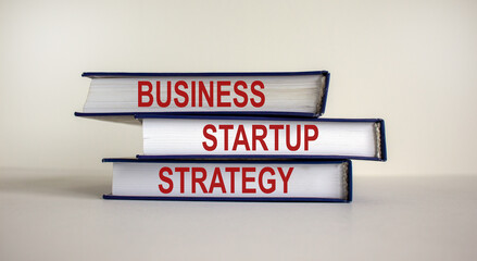 Books with text 'strategy startup business' on beautiful white background. Business concept. Copy space.