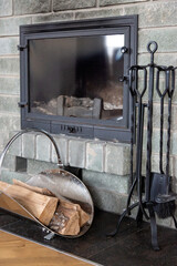 hearth of smoked gray brick with a glass and metal door. small woodpile and black cast iron...
