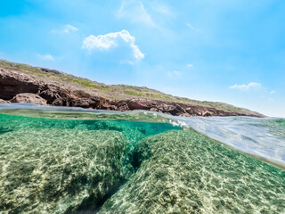 Split underwater view of rocks and clear water in Sardinia