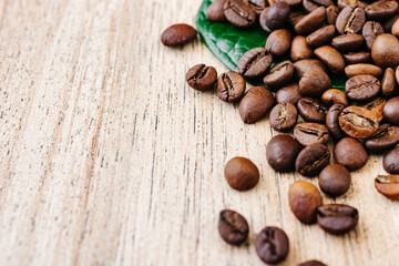 Coffee beans scattered on a light wooden table, top view, closeup grains, place to insert text, copy space