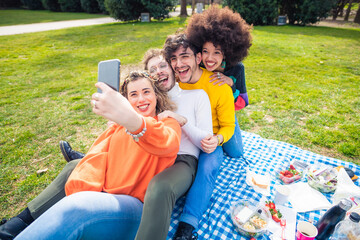Four people multiethnic friends oputdoor using smartphone taking selfie