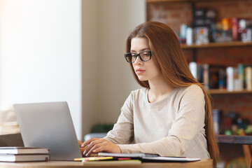 Portrait of young girl student sitting at cafe with laptop