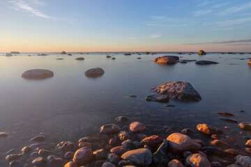Fototapeta na wymiar Baltic sea coast with stones and a beautiful sunset, long exposure photograph as a background for a postcard