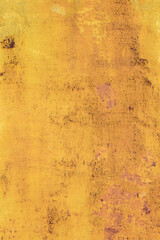 Old rusty metal surface with yellow and brown paint flaking and cracking texture. 