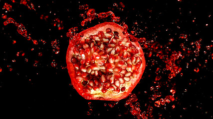 Freeze motion of sliced pomegranate with splashing juice isolated on black background