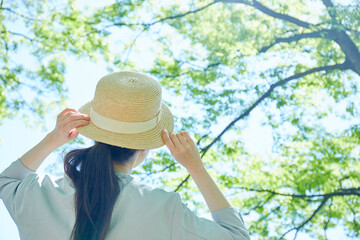 新緑の中で帽子を持つ若い女性の手元