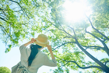 新緑の中で帽子を持つ若い女性の手元