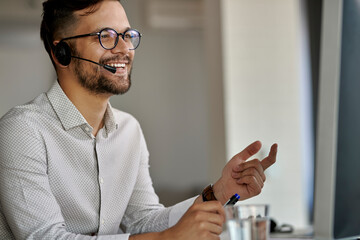 Happy customer service representative working on desktop PC at call center.