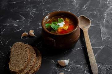 borsch in a clay pot with sour cream, brown bread and fresh herbs