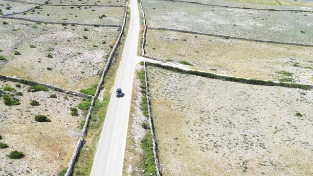 Scenic road on the island of Pag in Croatia, car drive between old agriculture fields and stone drywals

