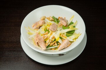 Warm salad with salmon lettuce, corn and cream cheese .On a white plate. On black background