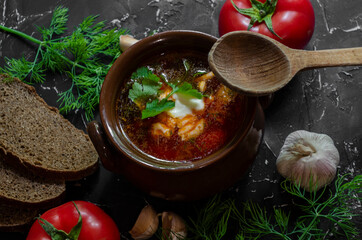 borsch in a clay pot with sour cream, brown bread and fresh herbs
