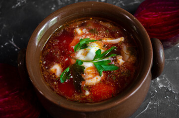 borsch in a clay pot with sour cream, brown bread and fresh herbs
