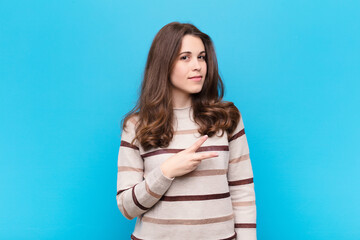 young pretty woman feeling happy, positive and successful, with hand making v shape over chest,...