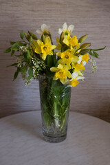 Bouquet of flowers in a glass vase on the table. Daffodils, tulips and white bird cherry.