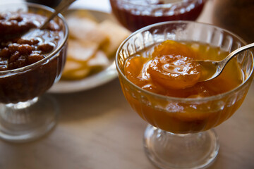 Apricot jam in a glass bowl with a spoon on the table.