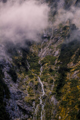 Waterfall on the side of a mountain at Milford sound , New Zealand