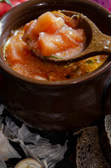 borsch in a clay pot with sour cream, brown bread and fresh herbs