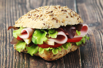 A sandwich with whole grain bread, ham and vegetables	