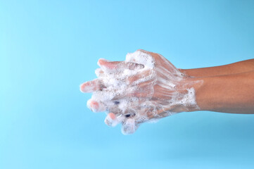 Washing hands with soap on blue background. Closeup of person washing hands. Cleaning Hands. Cleanliness and body care concept.