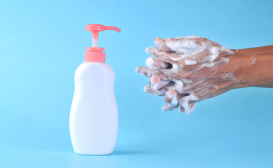Washing hands with soap on blue background. Closeup of person washing hands. Cleaning Hands. Cleanliness and body care concept.