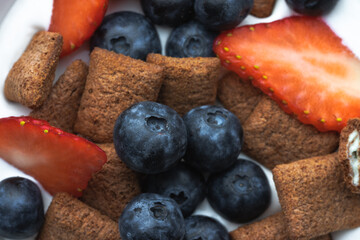 Cereal bowl with milk, blueberries and strawberries accompanied by tropical juice and ingredients. Gastronomic concept
