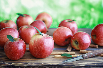 Fresh apples on a wooden board. Harvest of red apples. Fruits and cinnamon on the table.